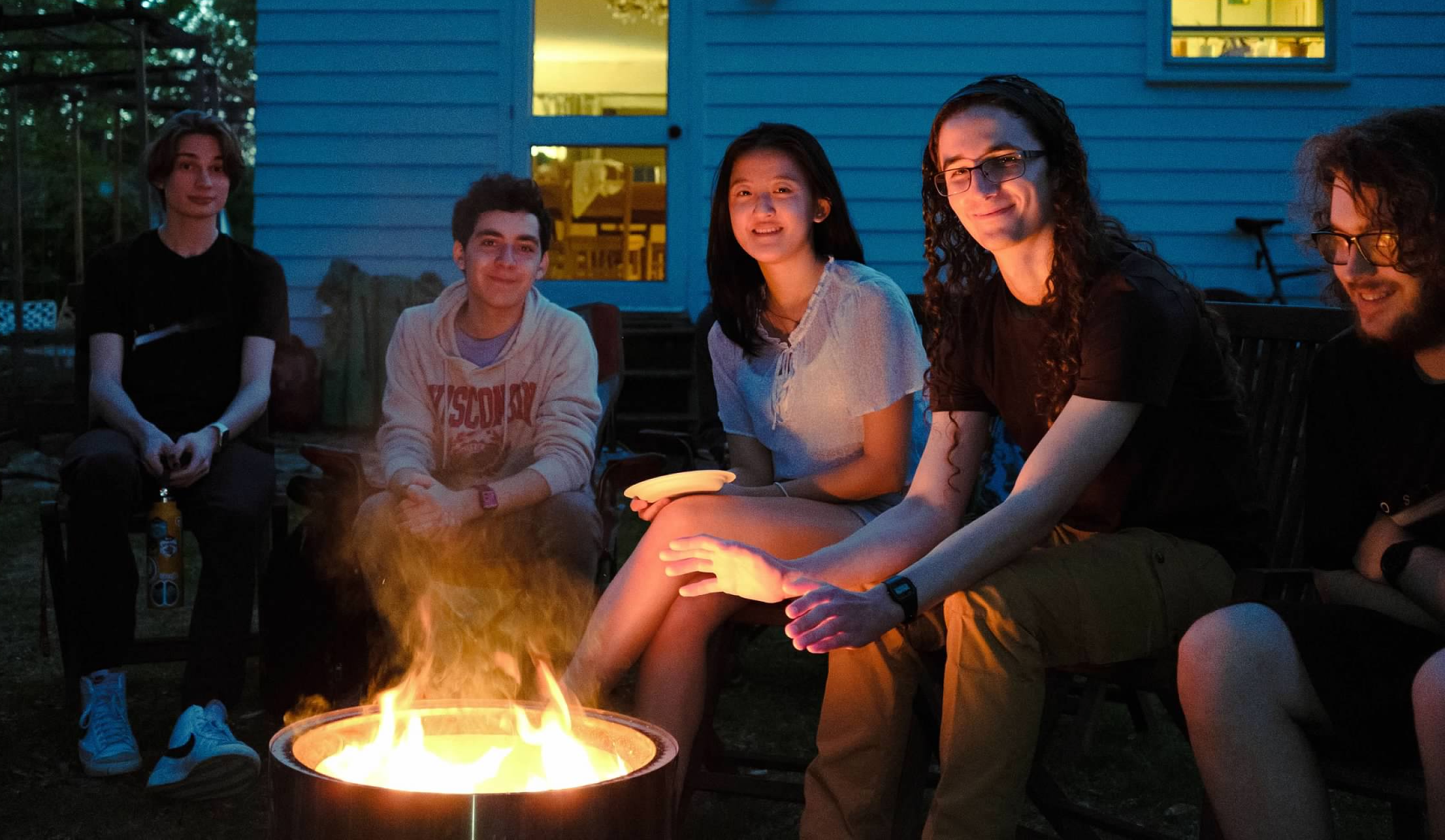 An image of Andrew outside. He wears a blue shirt, a gray flannel, and a lanyard with his name.